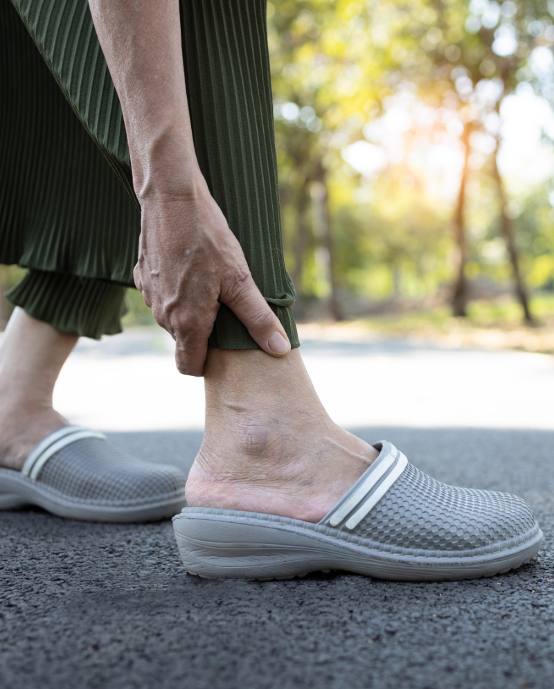 Woman holding the back of her ankle