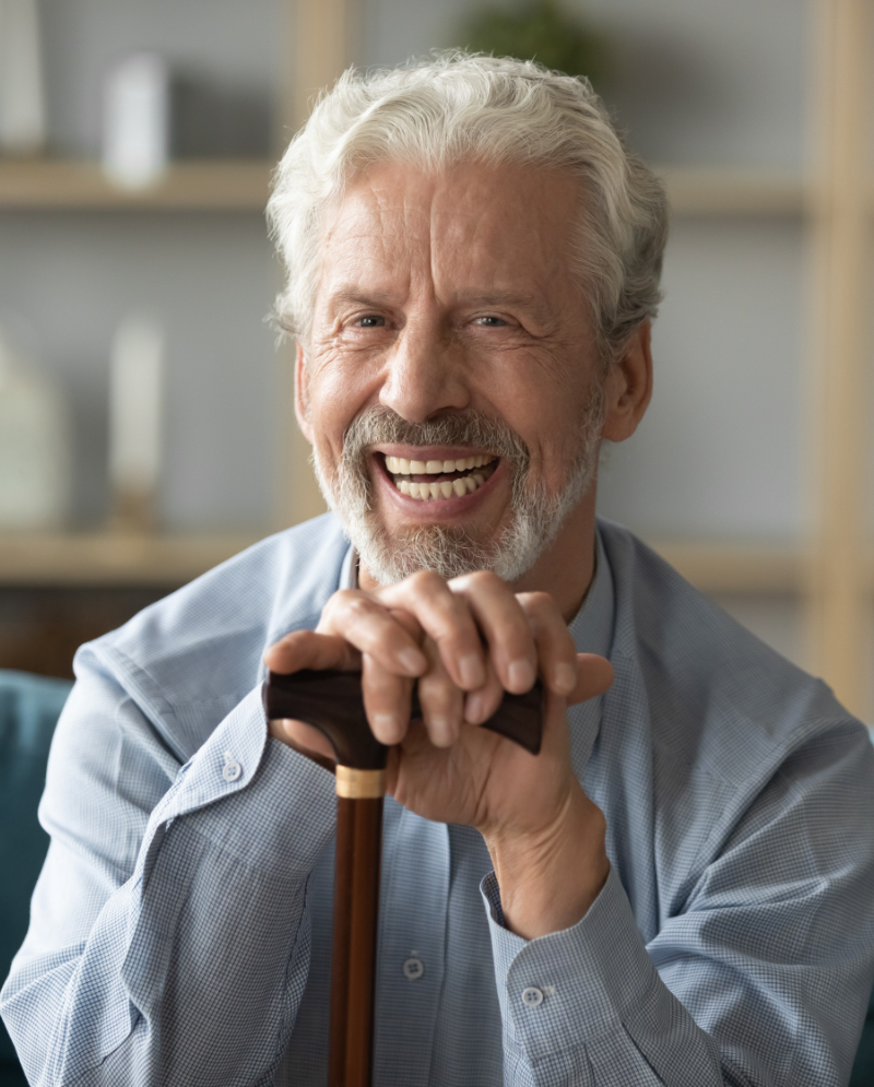 Smiling older man resting his hands on a cane