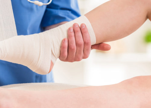 Doctor bandaging a patient's ankle